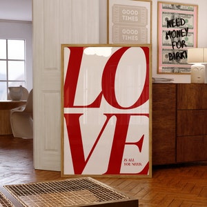 May include: A framed print featuring the word "LOVE" in large red letters against a white background. The text "IS ALL YOU NEED." is printed in smaller red letters below the word "LOVE".