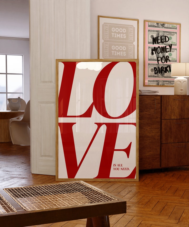 May include: A framed print featuring the word "LOVE" in large red letters against a white background. The text "IS ALL YOU NEED." is printed in smaller red letters below the word "LOVE".