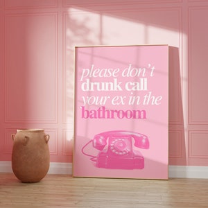Op de afbeelding: Een roze poster met een witte rand en de tekst "please don't drunk call your ex in the bathroom" met een roze draaischijftelefoon illustratie.
