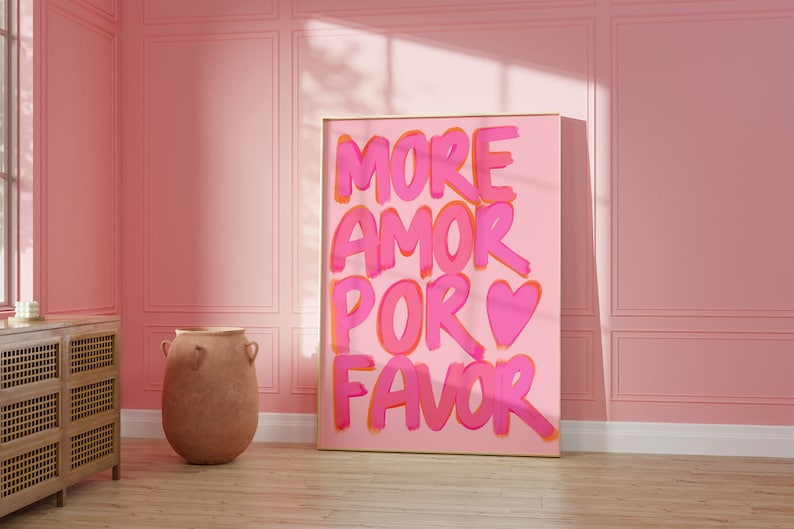 May include: A pink and orange framed canvas print with the text "MORE AMOR POR FAVOR" in a pink and orange handwritten font. A pink heart is included in the text.
