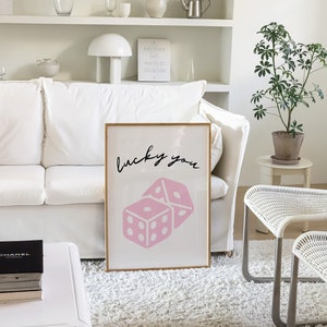Pu&ograve; includere: Una stampa incorniciata con un design di dadi rosa e il testo "lucky you" in scrittura corsiva nera.
