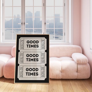 May include: A black framed print with three white tickets that say "Good Times" on a pink couch in a room with windows.