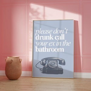 May include: A framed poster with a blue background and white text that reads "please don't drunk call your ex in the bathroom". A vintage rotary phone is pictured below the text.