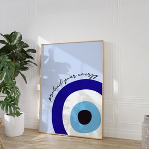 May include: A blue and white evil eye print with the text "protect your energy" in black. The print is framed in a gold frame.