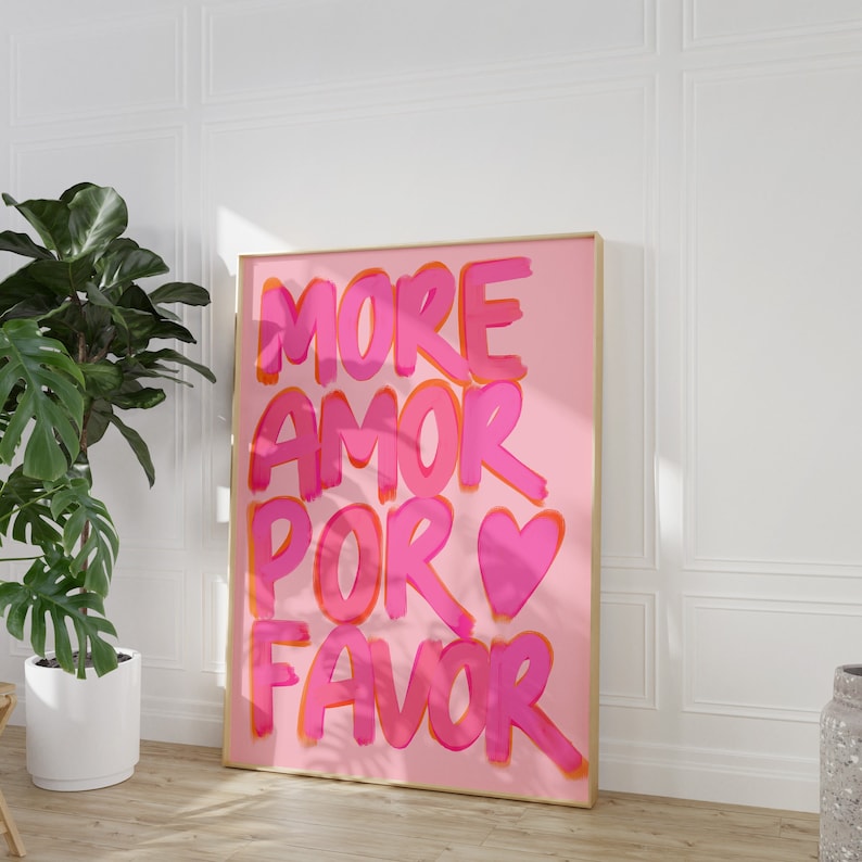 May include: Pink and orange text on a pink background reads "More Amor Por Favor" with a pink heart in the middle of the text.