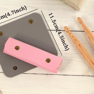 May include: A gray leather case with a pink leather pouch inside. The case measures 4.7 inches by 4.5 inches. The pouch has gold-colored snaps.