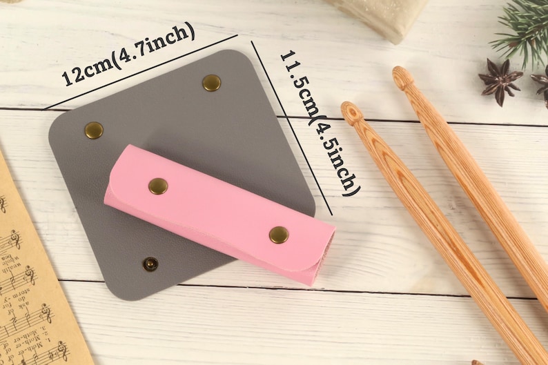 May include: A gray leather case with a pink leather pouch inside. The case measures 4.7 inches by 4.5 inches. The pouch has gold-colored snaps.