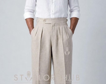 May include: A white long-sleeved button-down shirt paired with high-waisted beige trousers featuring double pleats, a wide waistband with side adjusters, and cuffed hems. The text "TAILOR HUB" is visible on the trousers with a small logo.