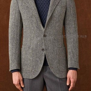 Puede incluir: Un blazer gris con diseño de espiga, con un jersey de cuello alto azul marino y pantalones grises. El blazer tiene dos bolsillos delanteros y cierre de dos botones. Adecuado para negocios o informal.