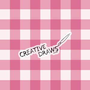 以下が含まれることがあります： ピンクと白のギンガムチェック柄に、「CREATIVE DRAWS Design」と書かれた白いステッカーと、筆のイラストが描かれています。