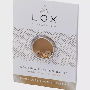 May include: A white box with gold geometric patterns and the text "LOX CLASSIC" at the top. The box contains two pairs of gold-tone locking earring backs. The text "LOCKING EARRING BACKS GOLD TONE | 2 PAIRS" is printed on the box. The text "NEVER LOSE ANOTHER EARRING" is printed on the box.