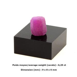 Puede incluir: Un rubí rosa vibrante, exhibido sobre un pedestal cuadrado negro. La gema tiene un peso promedio de 6,25 quilates y unas dimensiones de 9 x 8 x 6 mm.