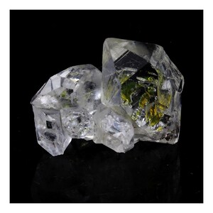 May include: A cluster of clear quartz crystals with green inclusions. The crystals are faceted and have a sharp, geometric shape. The crystals are arranged in a cluster, with the largest crystal in the center.