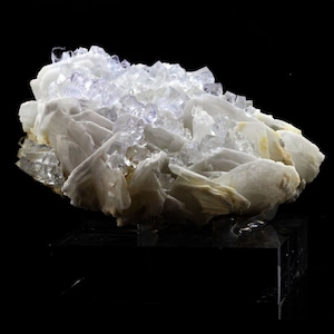 Puede incluir: Un grupo de cristales de barita blancos con una capa de cristales de fluorita claros y de color p&uacute;rpura claro en la parte superior. Los cristales est&aacute;n dispuestos en una forma natural y org&aacute;nica.