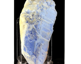 May include: A large, blue and white crystal with a rough, textured surface. The crystal is displayed on a clear acrylic stand against a black background.