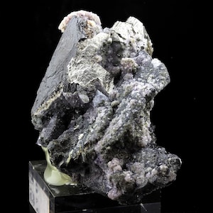May include: A large, dark gray, metallic mineral specimen with a sharp, pointed crystal. The specimen is covered in smaller, purple crystals.