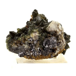 May include: A cluster of dark green, black, and clear quartz crystals. The crystals have sharp, pointed tips and are arranged in a dense formation. The base of the cluster is a mix of brown and gray minerals, with a few small, shiny black metallic inclusions.