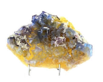 May include: A cluster of yellow and blue fluorite crystals on a stand. The crystals are intergrown and have a variety of shapes and sizes.