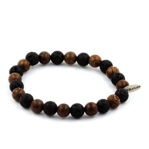 Peut inclure: Un bracelet de perles alternant des perles noires en pierre de lave et des perles en bois marron. Le bracelet comporte une étiquette argentée avec le mot "bijoux". Les perles sont enfilées sur un cordon élastique.
