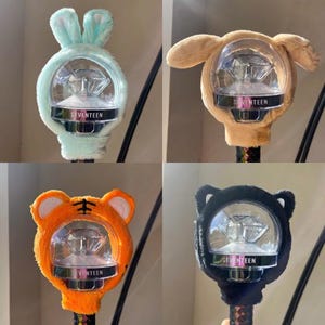 May include: Four light-up K-pop concert light sticks with different animal head designs. The light sticks are all white with a clear plastic sphere containing a diamond-shaped light. The light sticks are labeled "SEVENTEEN".