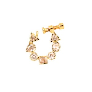 May include: A gold-colored nose ring featuring a series of clear, geometric-shaped gemstones. The design includes triangles, circles, and a square, all set in a circular arrangement. The nose ring has a screw-like closure.