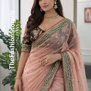 May include: A woman in a peach saree with gold detailing and a black embroidered blouse. The saree features a sheer overlay and a decorative border. The image includes the text "TheFashionStoreIN" on the left side.