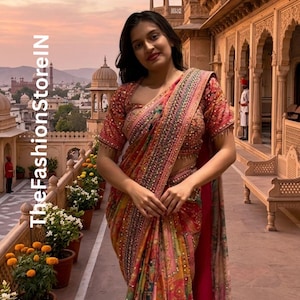 Pode incluir: Uma mulher usando um sari ornamentado com bordados e miçangas intrincados. O sari apresenta uma mistura de tons vermelhos, rosa, amarelos e verdes. O fundo mostra um edifício com arcos e uma paisagem urbana.