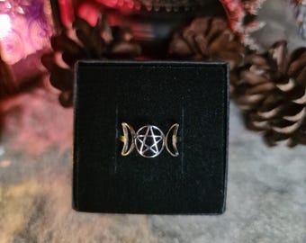 May include: A silver ring with a triple moon and pentagram design. The ring is displayed in a black velvet box.