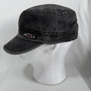 Könnte beinhalten: Dunkelgraue Denim-Kadettenmütze mit kurzem Schirm. Die Kappe hat ein dekoratives Band mit kleinen Metallakzenten. Der Hut wird auf einem weißen Schaufensterkopf präsentiert.