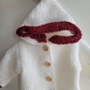 Knitted baby jacket - Acrylic yarn - White jacket with red accents and hood.