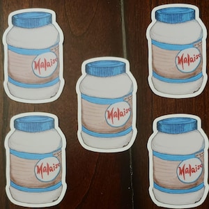 May include: Five white jars with blue lids and a red label that says "Malaise" on them. The jars are on a wooden surface.
