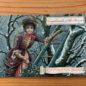 De antieke ansichtkaart Maretak Bough. "De maretaktak". Antieke winterkaart van Girl Up a Tree! Complimenten van het seizoen. PC265.