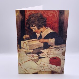 May include: Greeting card featuring a vintage illustration of a child wrapping gifts. The child, dressed in a dark blue outfit with a white collar, is focused on tying a package. Several wrapped gifts and a spool of red thread are visible.