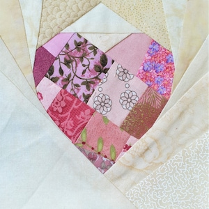 May include: A patchwork heart quilt block with a spiral design. The heart is made of pink, red, and brown fabric with floral and geometric patterns.