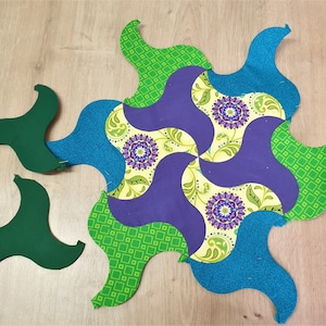 Peut inclure: Un bloc de courtepointe en patchwork avec un motif en spirale dans des tons de vert, bleu, jaune et violet. Le bloc est composé de plusieurs pièces de tissu différentes, chacune avec un motif unique.