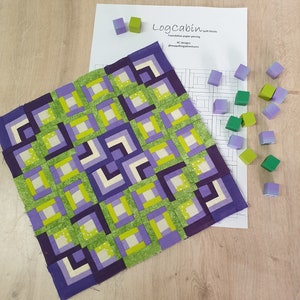 May include: A quilt block pattern for a log cabin quilt. The pattern is printed on white paper and includes instructions for foundation paper piecing. The pattern is surrounded by wooden blocks in shades of green and purple.