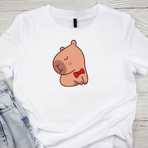 May include: White t-shirt with a cartoon illustration of a brown capybara wearing a red bow tie.
