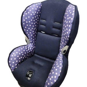 May include: A blue and white polka dot car seat with a black padded seat and headrest.