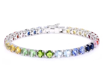 Può includere: Un bracciale in argento con una fila di pietre preziose multicolori. Le pietre sono disposte in uno spettro arcobaleno, con tonalità di rosso, arancione, giallo, verde, blu e viola. Il bracciale ha una chiusura.