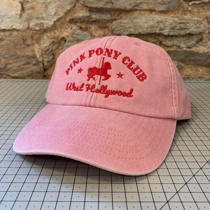 May include: Pink baseball cap with a red embroidered logo that says "Pink Pony Club West Hollywood" with a red cartoon pony on a carousel horse.