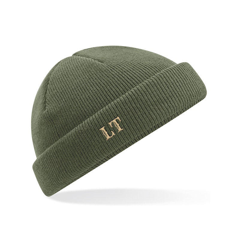 May include: A green knitted beanie with a fold-over brim and the initials "LT" embroidered in gold on the front.