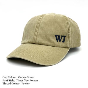 May include: A vintage stone coloured baseball cap with a black thread embroidered with the initials "WJ" in Times New Roman font.