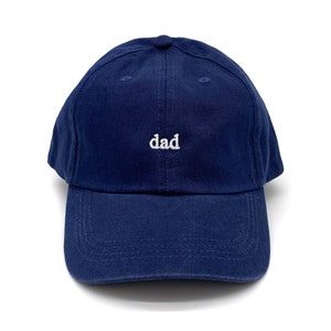 May include: A navy blue baseball cap with the word "dad" embroidered in white on the front.