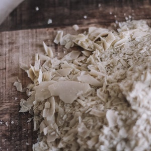 May include: Close-up of a wooden cutting board with a pile of shredded coconut flakes.