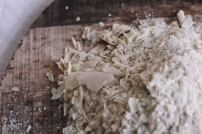 May include: Close-up of a wooden cutting board with a pile of shredded coconut flakes.