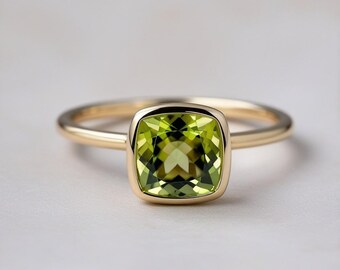 Exquisito anillo de peridoto natural: piedra preciosa con forma de cojín facetada y elegante bisel dorado. Colección de joyas elegantes.