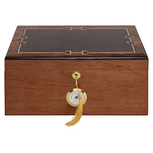 May include: A wooden humidor with a gold-colored key and a hygrometer with a tassel. The humidor has a dark brown wood top with a gold-colored design.
