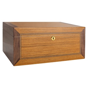 Op de afbeelding: Een houten doos met een donkerbruine afwerking en een lichtbruine inleg. De doos heeft een messing sleutelgat en een scharnierend deksel.