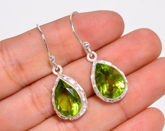 May include: A pair of silver dangle earrings with pear-shaped green peridot gemstones.