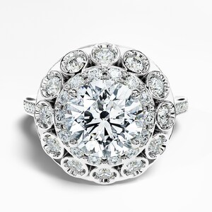May include: A dazzling diamond ring featuring a large, round-cut center stone surrounded by a halo of smaller diamonds. Additional diamonds adorn the ring's band and outer halo, creating a brilliant display of light and sparkle. The ring is set in a white metal.